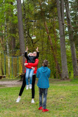 Parkta iki kız kardeş ve bir erkek kardeş sıcak bir bahar gününün tadını çıkarın ve bir dronla eğlenin, yaşam tarzı ve eğlence kavramı.