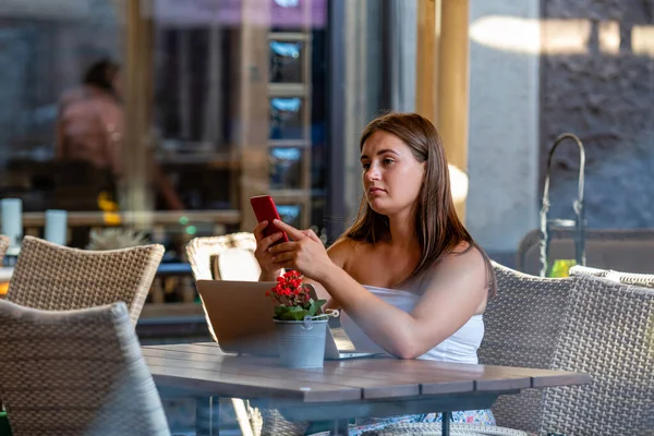 Mujer Joven Trabaja Ordenador Portátil Uso Teléfono Sentado Cafetería Calle —  Fotos de Stock