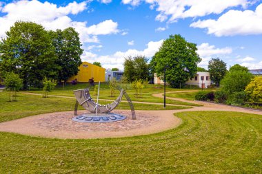 Küçük Letonya kasabası Auce 'nin şehir manzarası. Şehir parkında biçimlendirilmiş bir güneş saati var. Posta borusu şeklinde.
