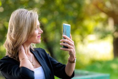 Sarışın, neşeli kadın yaz günü cep telefonu kullanıyor.