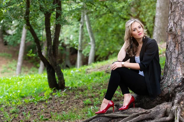 Zarif sarışın bayan ağaçların orada oturuyor ve sessizliğin tadını çıkarıyor.