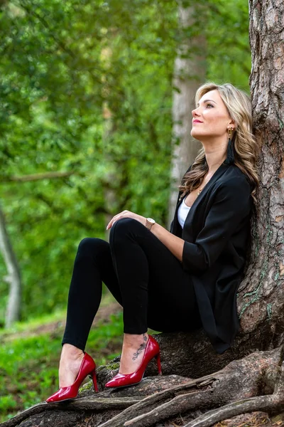 Zarif sarışın bayan ağaçların orada oturuyor ve sessizliğin tadını çıkarıyor.