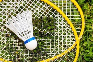 Yeşil çimenlikteki sarı badminton raketlerinin üzerine beyaz pipi yakın plan, tepeden tırnağa