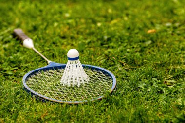 badminton raketleri ve yeşil çimlerin üzerinde mekik horozu