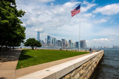 New York, ABD - 7 Haziran 2019: New York Limanı ve Manhattan silueti üzerinde Amerikan bayrağı