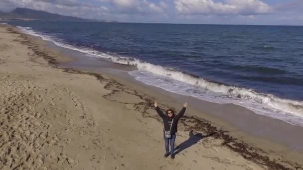 Menina na costa que cumprimenta assistindo o drone — Vídeo de Stock