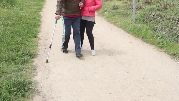 Elderly couple walking with crutches helping themselves — Stock Video