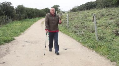 bir buket çiçek taşıyan koltuk değnekleriyle yürüyen yaşlı adam