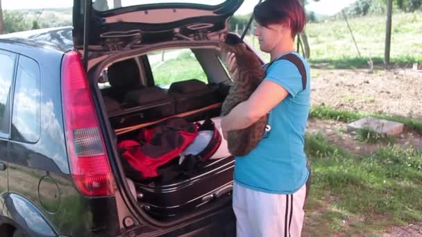 Chica dispuesta a ir con las bolsas cargadas en el coche con su gato en la mano — Vídeos de Stock