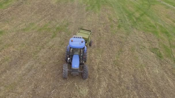 Человек за работой на тракторе с тюком сена — стоковое видео