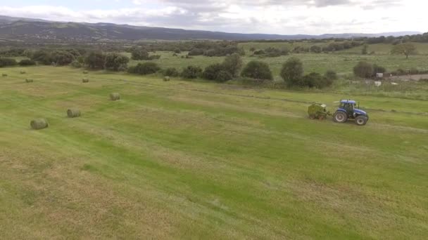 Bird eye of Man at work on the tractor with hay baler — Stock Video