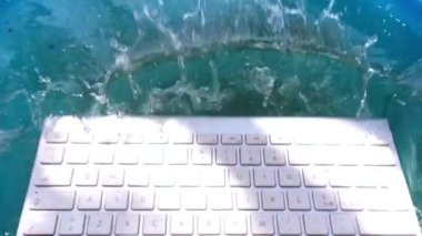 beyaz kablosuz bilgisayar klavyesi yavaş çekimde su püskürtme görünümü içine düşüyor