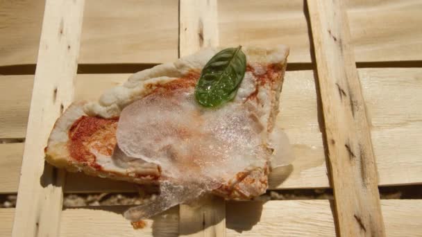 Scheibe italienischer Schinkenpizza, die im Zeitraffer in der Sonne gefriert — Stockvideo