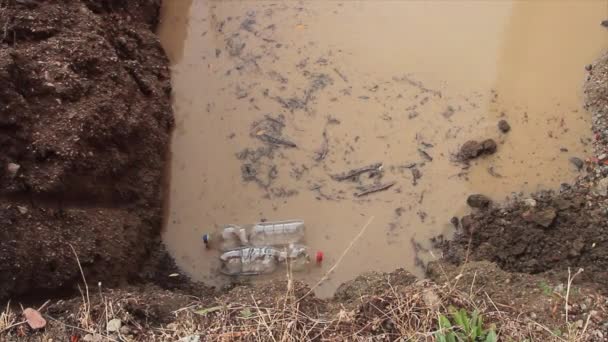 Bouteille en plastique transparent qui flotte et se déplace dans une flaque d'eau putride polluant l'environnement — Video