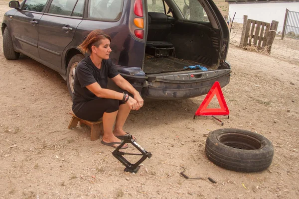 美しい女性とジャックを使用して車のタイヤを変更するためのツール — ストック写真