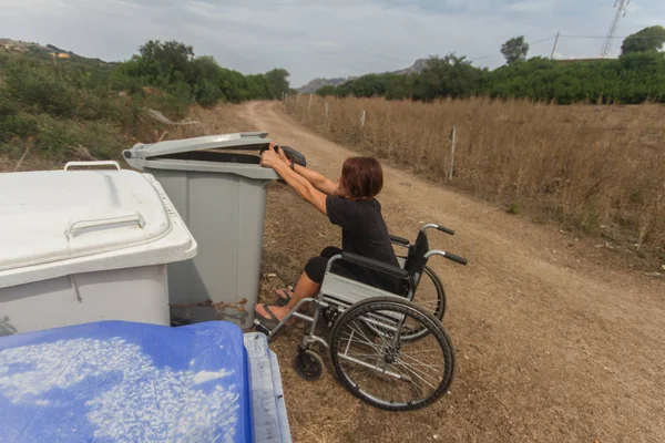 disabled girl in wheel chair in everyday life doing recycling