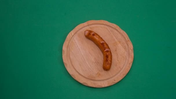 Zastavení pohybu párky wurstel a hranolků, které se jedí na dřevěné desce — Stock video