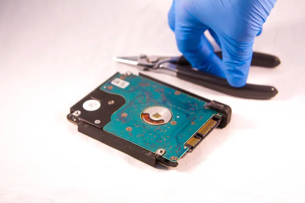 fixing a hard disk drive with one hand with gloves and a special tweezers