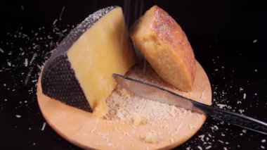 ahşap bir kesme tahtası üzerinde Sardunya pecorino peyniri bir dilim üzerine düşen rendelenmiş pecorino peyniri yavaş hareket