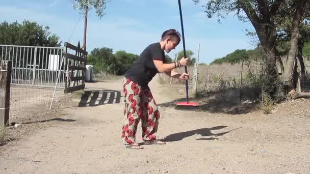 年轻的家庭主妇带着扫帚在院子里欢快地跳舞 — 图库视频影像