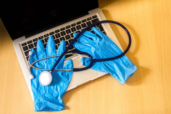 medical tools such as stethoscope, gloves and a mask resting on a computer keyboard as a symbol of the reparation of laptops and doctors with computers and medi kit
