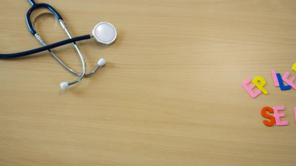 Stop motion time lapse of word avec des lettres épileptiques colorées sur une table avec un stéthoscope et des médicaments en mouvement — Video