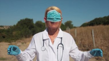 Genç sarışın doktor. Sağlık maskesi takmış. Gözlerinde ve kulaklarında.