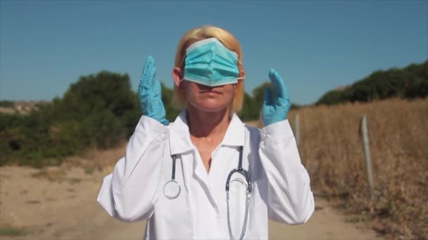 눈과 손에 건강 마스크를 착용하고 있는 젊은 금발의 의사 귀나 머리에 안 된다고 말하는 의사 — 비디오