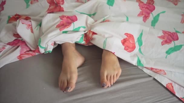 Twee meisje voeten in bed bedekt met lakens en ze eindigt masturberen en zet de seksuele vibrator tussen haar voeten — Stockvideo