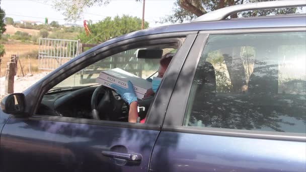 Хлопчик доставки піци доставляє дві коробки італійської піци прямо з вікна автомобіля з маскою для здоров'я над ротом, щоб запобігти вірусу covid19 — стокове відео