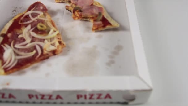 Boczne poślizgnięcie się ręki pizzy kucharza w niebieskich rękawiczkach delikatnie umieszcza włoską pizzę na pudełku po pizzy obok pustej z tylko skórkami — Wideo stockowe