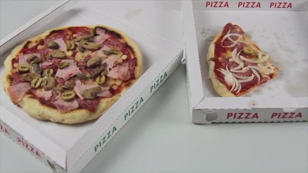 Lado deslizante de la mano de un chef de pizza con guantes azules retira suavemente una corteza de pizza italiana de la caja de pizza junto a una completa — Vídeos de Stock