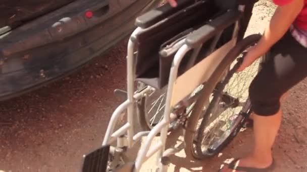 車椅子に障害者を乗せて車椅子を畳んで車のトランクに入れるのを助ける人の日常生活 — ストック動画
