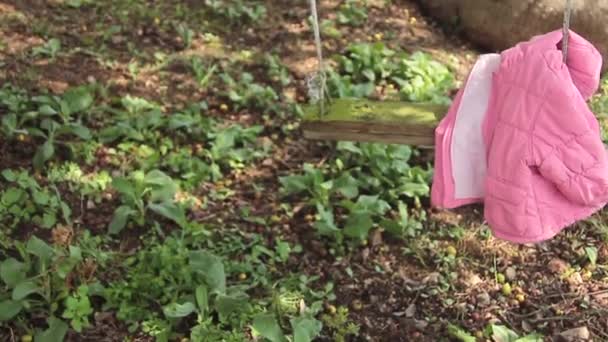 Detektiv lehnt die gelbe Asservatenkarte unter einer Schaukel, die allein schwingt, nachdem er ein kleines Mädchen entführt hat, das eine rosafarbene Jacke und einen Stiefel mit ihrer Lieblingspuppe daneben zurücklässt — Stockvideo