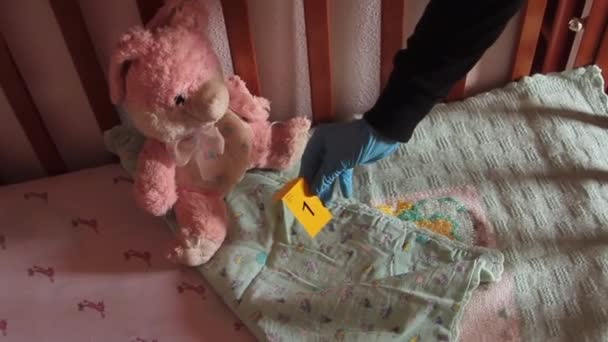 Widok z góry łóżeczka, które jest dowodem porwania dziecka, gdzie detektyw umieszcza dowody oznaczone żółtą kartą — Wideo stockowe