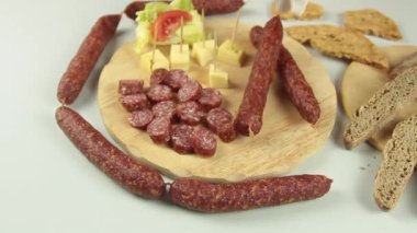 Şeflerin ellerinin tipik bir Güney Tirol aperatifi servis edişinin kaygan görüntüsü Tirol füme sosisi gibi tahta kesme tahtasının üzerinde kaminwurz ve paarl tipi ekmek eşliğinde.