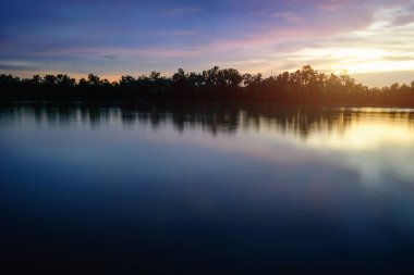 Mavi gökyüzü günbatımı ve yansıma manzara nehir yanında göster