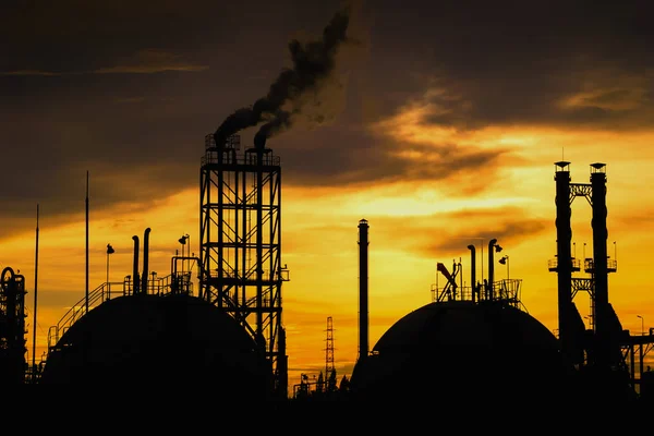 Gas storage sphere tanks and smoke stacks in silhouette image on sunset sky background