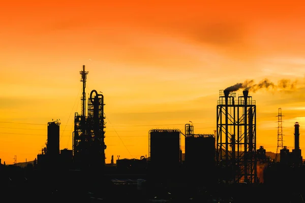オレンジ色の空夕日を背景にシルエット イメージで煙を出している石油化学工場や石油 ガス精製業界 — ストック写真
