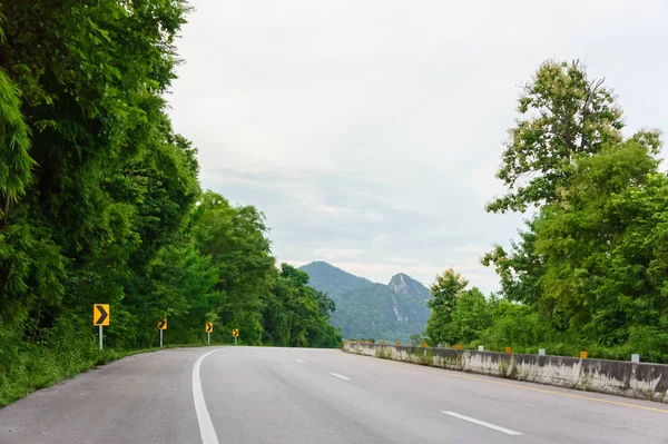 Asphalt road are garden tree and forest in Thailand with green grass with copy space. For background and landscape.
