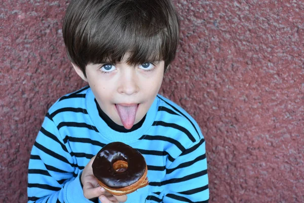 かわいい小さな男の子食べるドーナツ — ストック写真