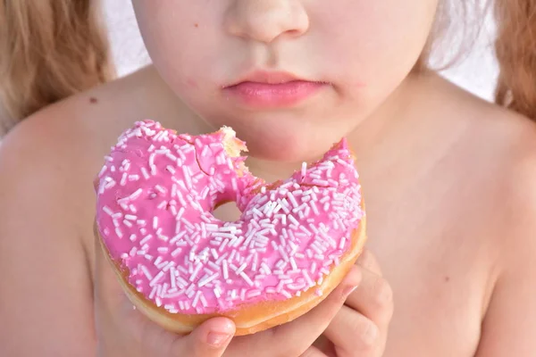 小さな女の子はピンクのドーナツを食べる — ストック写真