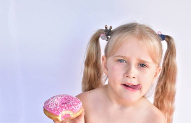 küçük kız pembe bir çörek yiyor
