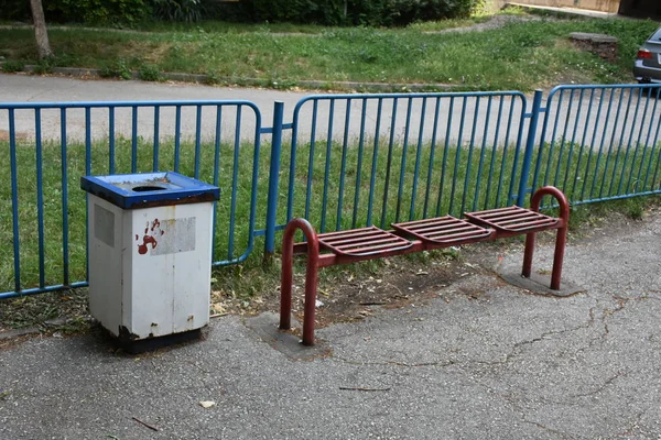 metallic bench and trash bin in street  at fence