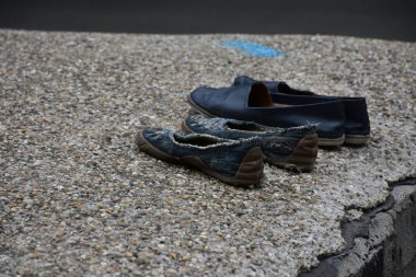Asfalttaki yıpranmış ayakkabıların kırpılmış görüntüsü 