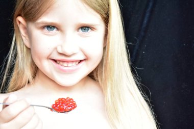 Çocuk balıktan kırmızı havyar yiyor.