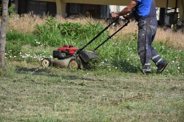 Bahçede çim biçen bir adam. 