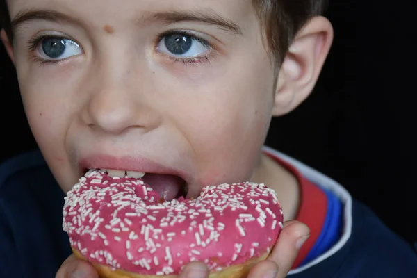 小さな男の子食べるドーナツ — ストック写真