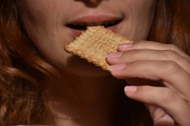 Closeup of redhead woman eating cookie