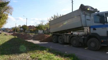 Yol asfaltlaması için taş taşıyan büyük bir inşaat kamyonu.